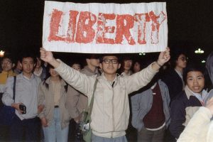 Student prezentuje baner z jednym ze sloganów skandowanych przez tłum liczący ok. 200 tys. osób, który wylewał się na plac Tiananmen w Pekinie, 22.04.1989 r. (CATHERINE HENRIETTE/AFP/Getty Images)