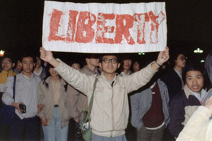 Student trzymający transparent w tłumie około 200 000 osób, który zebrał się na placu Tiananmen 22 kwietnia 1989 r. Jak utrzymuje się w tajnej brytyjskiej depeszy dyplomatycznej, ten trwający od kwietnia do czerwca 1989 r. ruch został zdławiony przez wojsko chińskie, które zabiło w tej akcji co najmniej 10 000 osób<br/>(Catherine Henriette/AFP/Getty Images)