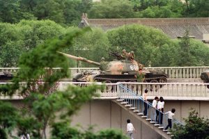 Chińscy gapie uciekają przed żołnierzem grożącym im pistoletem dnia 5 czerwca 1989 r. po zajęciu przez czołgi pozycji na kluczowych skrzyżowaniach Pekinu obok kompleksu dyplomatycznego (Catherine Henriette/AFP/Getty Images)