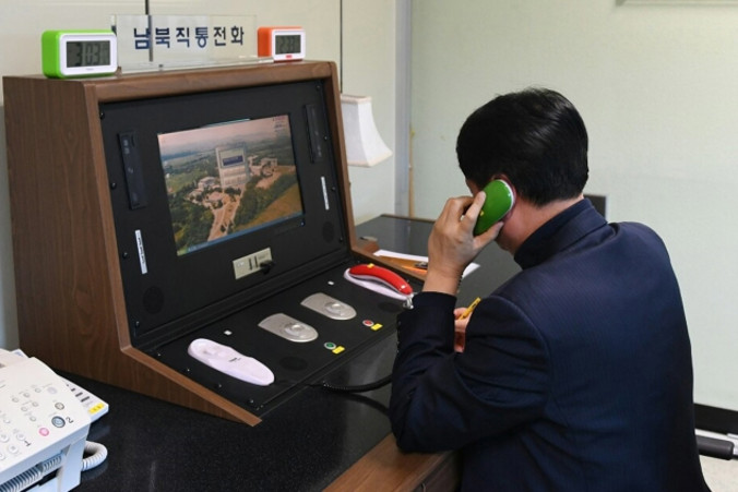 Oficjalne zdjęcie udostępnione przez południowokoreańskie Ministerstwo ds. Zjednoczenia przedstawia południowokoreańskiego urzędnika rządowego komunikującego się z oficerem północnokoreańskim w strefie zdemilitaryzowanej (DMZ) w wiosce przygranicznej Panmundżom w Korei Południowej, 3.01.2018 r. (Ministerstwo ds. Zjednoczenia/PAP/EPA)