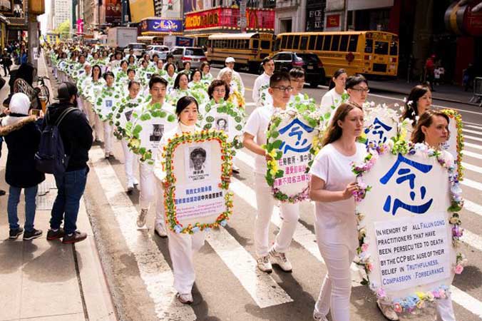 Praktykujący Falun Gong podczas parady na Manhattanie w Nowym Jorku trzymają wieńce ze zdjęciami osób, które zostały zabite w Chinach z powodu swoich przekonań, 12.05.2017 r. (Samira Bouaou / The Epoch Times)
