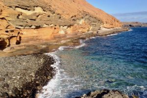 Opadające ku oceanowi zbocze Montana Amarilla przylega do maleńkiej czarnej plaży Callao de la Cochina w Costa del Silencio. Jeżeli dobrze wytężycie wzrok, dostrzeżecie ludzi opalających się na półkach skalnych. Teneryfa, styczeń 2018 r. (archiwum autorki)