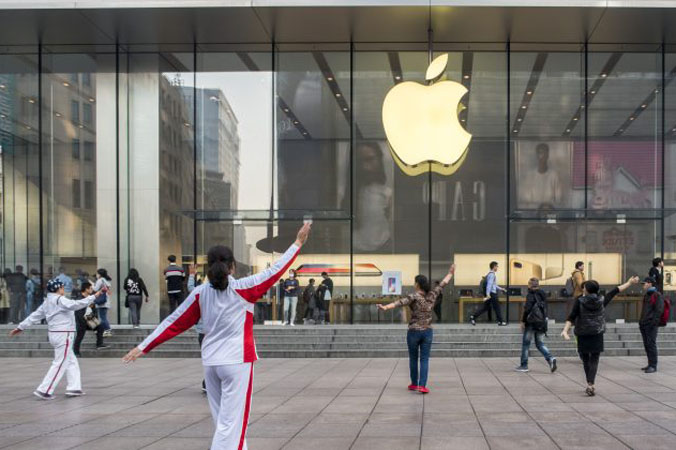 Ludzie tańczą przed sklepem Apple, 3.11.2017 r. w Szanghaju w Chinach. Apple zrzeka się kontroli nad swoimi serwerami iCloud dla chińskich użytkowników na rzecz państwowej firmy w Chinach, powołując się na zgodność z prawami chińskiego reżimu. (VCG via Getty Images)