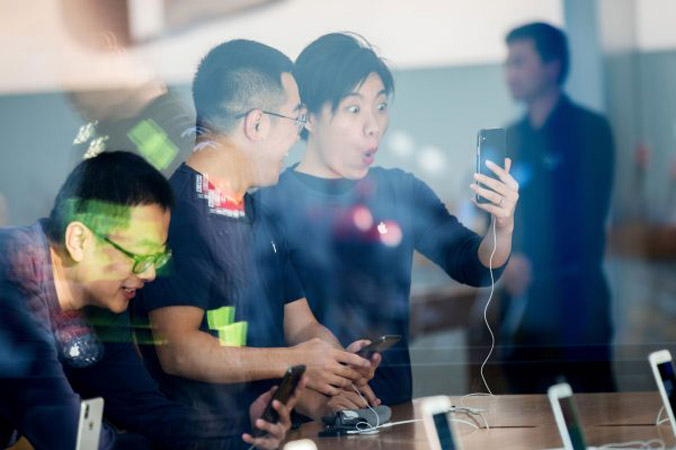 Chińscy pracownicy oglądają nowego iPhona X w sklepie Apple w Hangzhou we wschodniej prowincji Chin, Zhejiang, 3.11.2017 r. (STR/AFP/Getty Images)