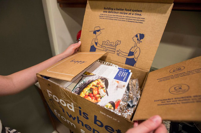 Klient Blue Apron otwiera w kuchni paczkę dostarczoną przez tę firmę, Boston, 28.06.2017 r. (Scott Eisen / Getty Images)