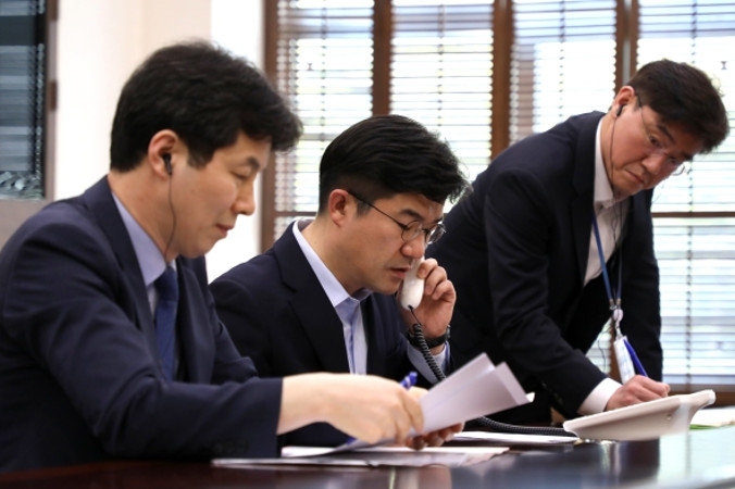 Południowokoreański urzędnik podczas próby połączenia z północnokoreańską Komisją Spraw Państwowych za pośrednictwem linii umożliwiającej bezpośrednią rozmowę między przywódcami dwóch Korei, Seul, Korea Płd., 20.04.2018 r. (ROK PRESIDENTIAL OFFICE / PAP/EPA)