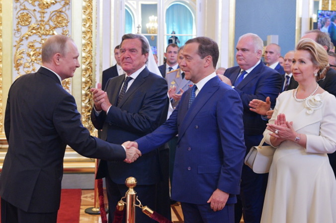 Prezydent Rosji Władimir Putin (z lewej) wymienia uścisk dłoni z premierem Rosji Dmitrijem Miedwiediewem (z przodu, drugi z prawej). Na zdjęciu także Swietłana Miedwiediewa, żona premiera Rosji (z prawej), oraz były kanclerz Niemiec i szef rady dyrektorów Rosnieftu Gerhard Schröder (drugi z lewej), Moskwa, 7.05.2018 r. 