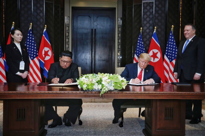 Sekretarz stanu USA Mike Pompeo (pierwszy z prawej) i siostra lidera KRLD Kim Jo Dzong (pierwsza z lewej) patrzą na prezydenta USA Donalda J. Trumpa (drugi z prawej) i na północnokoreańskiego przywódcę Kim Dzong Una (drugi z lewej) podpisujących wspólne oświadczenie podczas historycznego szczytu Korea Północna – Stany Zjednoczone w hotelu Capella na wyspie Sentosa w Singapurze, 12.06.2018 r. (KEVIN LIM / THE STRAITS TIMES / SPH/PAP/EPA)