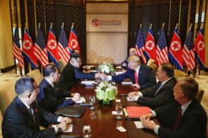 Prezydent USA Donald J. Trump (trzeci z prawej) i przywódca Korei Płn. Kim Dzong Un (trzeci z lewej) uścisnęli sobie dłonie przy stole podczas rozszerzonego dwustronnego spotkania w ramach historycznego szczytu w hotelu Capella na wyspie Sentosa w Singapurze, 12.06.2018 r. (KEVIN LIM / THE STRAITS TIMES / SPH/PAP/EPA)