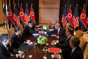 Prezydent Donald Trump wymienia uścisk dłoni z przywódcą Korei Płn. Kim Dzong Unem podczas rozmów przy wspólnym stole podczas szczytu USA – Korea Płn. w hotelu Capella, na wyspie Sentosa, Singapur, 12.06.2018 r. (SAUL LOEB/AFP/Getty Images)