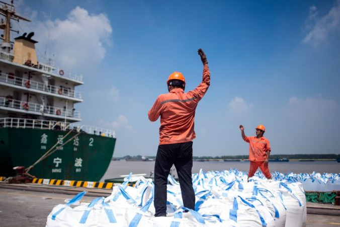 Pracownicy rozładowują worki z substancjami chemicznymi w porcie w Zhangjiagang we wschodniej prowincji Jiangsu, Chiny, 7.08.2018 r. (JOHANNES EISELE/AFP/Getty Images)