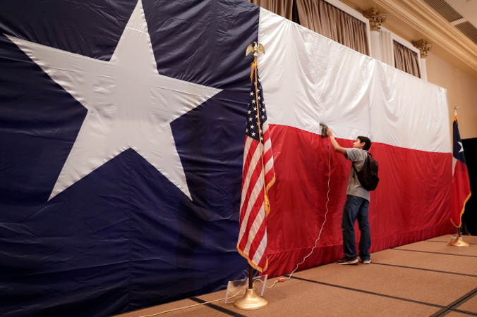 Paul Lopez, pracownik sztabu Teda Cruza, wygładza zmarszczki na fladze Teksasu, używanej jako tło sceny, podczas przygotowań w nocnej siedzibie sztabu wyborczego, wybory prezydenckie 2018 r., Hilton Post Oak w Houston, Teksas, 6.11.2018 r. (MICHAEL WYKE/PAP/EPA)