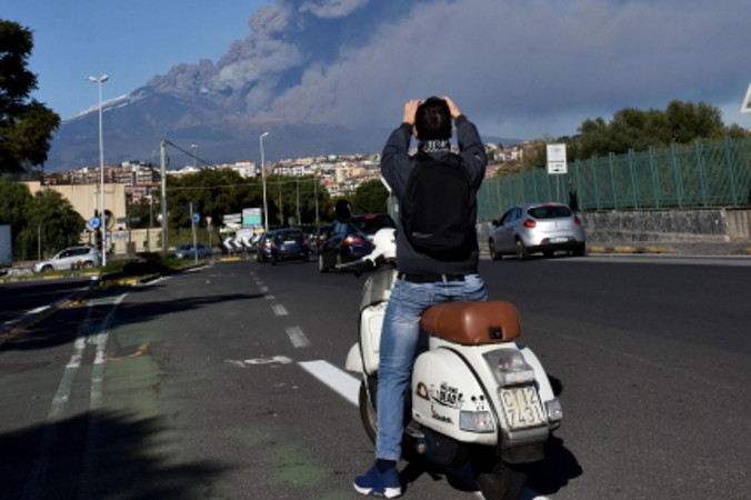 Mężczyzna robi zdjęcie wznoszącej się chmury dymu i popiołu ponad wulkanem Etna w Katanii na Sycylii, Włochy, 24.12.2018 r. (ORIETTA SCARDINO/PAP/EPA)