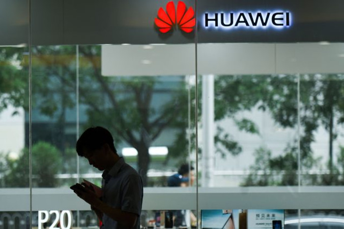 Mężczyzna korzysta z telefonu komórkowego pod sklepem Huawei w Pekinie, 7.08.2018 r. (Wang Zhao/AFP/Getty Images)