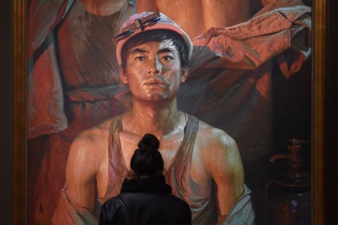 Zwiedzający wystawę zatytułowaną „Portrety ludzi” patrzy na obraz robotnika, Pekin, 23.11.2015 r. (GREG BAKER/AFP/Getty Images)