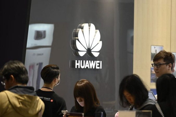 Ludzie stoją obok logo chińskiego giganta telekomunikacyjnego Huawei w Syntrend Creative Park w Tajpej, 9.02.2019 r. (Sam Yeh/AFP/Getty Images)