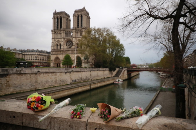 Turyści układają kwiaty na moście w pobliżu katedry Notre Dame po wielkim pożarze, który zniszczył jej dach, Paryż, 16.04.2019 r. (CHRISTOPHE PETIT TESSON/PAP/EPA)