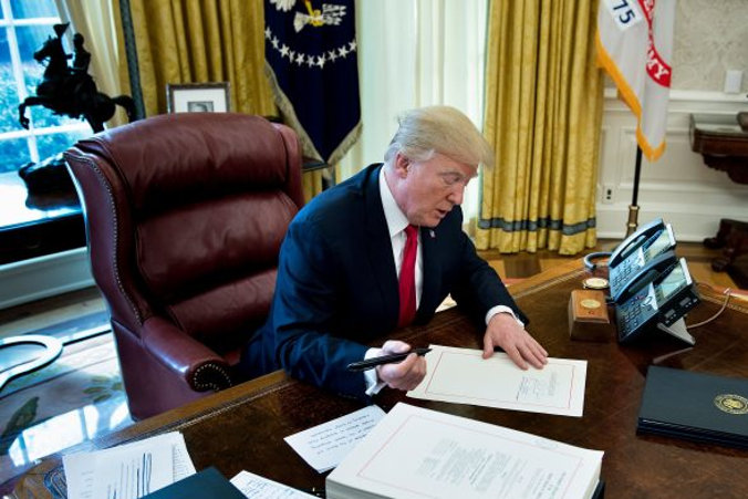 Prezydent Donald Trump podpisuje projekt ustawy o cięciach podatkowych i reformie podatkowej w Gabinecie Owalnym w Białym Domu, Waszyngton, 22.12.2017 r. (Brendan Smialowski/AFP/Getty Images)