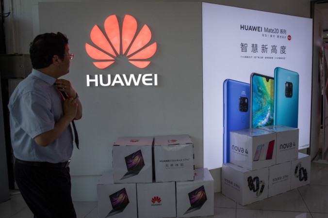 Mężczyzna stoi obok logo Huawei w centrum handlowym w Pekinie, 20.05.2019 r. (ROMAN PILIPEY/PAP/EPA)