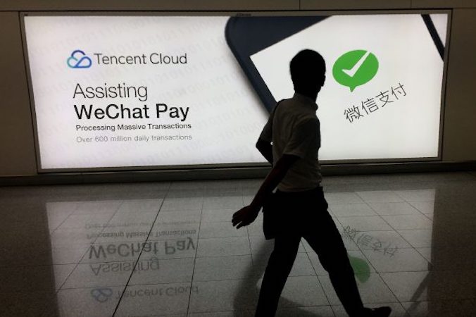 Na międzynarodowym lotnisku w Hongkongu mężczyzna mija reklamę platformy mediów społecznościowych WeChat, która należy do chińskiej firmy Tencent, 21.08.2017 r. (RICHARD A. BROOKS/AFP/Getty Images)