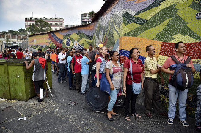 Ludzie stoją w kolejce, aby otrzymać kanistry na wodę i tabletki do uzdatniania wody od członków Wenezuelskiego Czerwonego Krzyża, Caracas, Wenezuela, 16.04.2019 r. (Jurij Corteza/AFP/Getty Images)