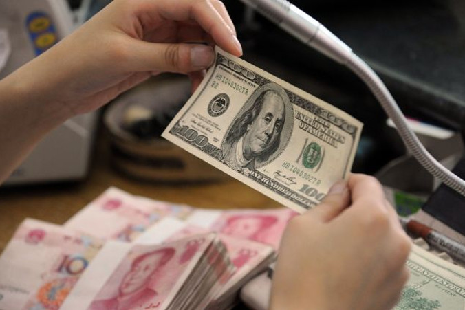 Pracownik chińskiego banku sprawdza 30 dolarów, obok pliki banknotów o nominale 100 juanów, kasa banku w mieście Hefei, prowincja Anhui, Chiny, 30.09.2010 r. (STR/AFP/Getty Images)