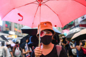 Protestująca z zasłoniętym prawym okiem idzie ulicą podczas wiecu w Hongkongu, 18.08.2019 r. Tydzień wcześniej, 11 sierpnia młoda kobieta doznała obrażeń oka, za które demonstranci obwinili policję strzelającą workami z fasolą (Manan Vatsyayana/AFP/Getty Images)