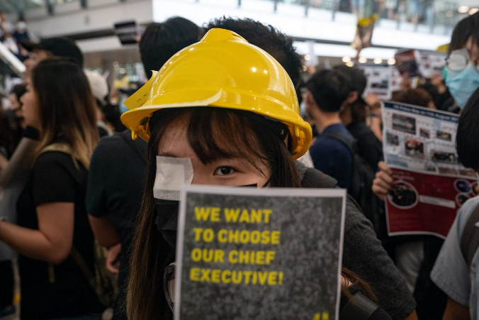 Protestująca trzyma plakat podczas demonstracji w hali przylotów międzynarodowego lotniska w Hongkongu, 12.08.2019 r. (Anthony Kwan/Getty Images)