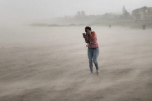 Kobieta, która spacerowała po plaży, próbuje chronić się przed wiatrem oraz smagającymi piaskiem i deszczem, niesionymi przez huragan Dorian, Cocoa Beach, Floryda, 2.09.2019 r. (Scott Olson/Getty Images)