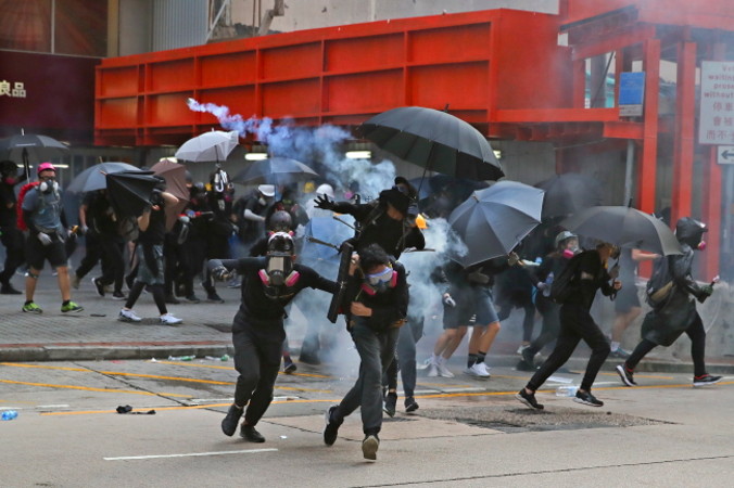 Demonstranci uciekają przed gazem łzawiącym podczas protestów w 70. rocznicę proklamowania komunistycznej ChRL, Hongkong, 1.10.2019 r. (FAZRY ISMAIL/PAP/EPA)