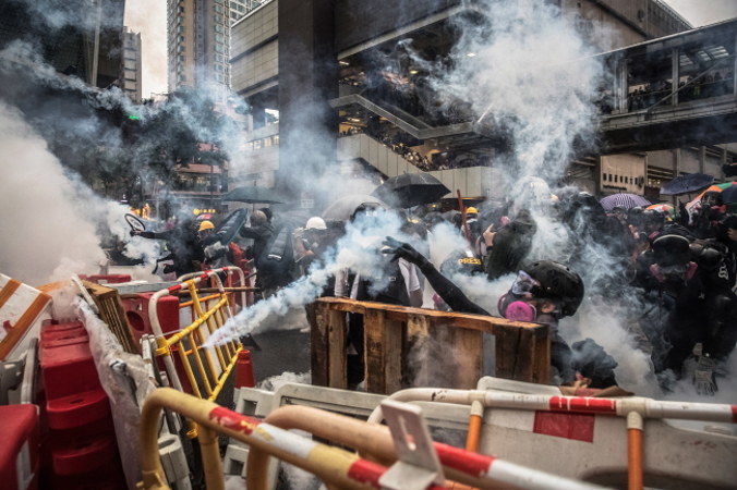 Protestujący w maskach przeciwgazowych reagują po tym, gdy policja wystrzeliła gaz łzawiący podczas wiecu antyrządowego w Tsuen Wan, Hongkong, 25.08.2019 r. (ROMAN PILIPEY/PAP/EPA)