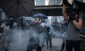 Prodemokratyczny protestujący odrzuca pojemnik z gazem łzawiącym z powrotem w kierunku policji podczas starć, marsz w Hongkongu, 29.09.2019 r. (Chris McGrath / Getty Images)