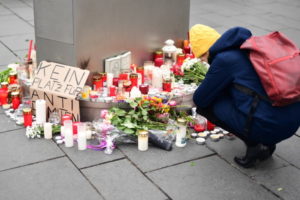 Kobieta zapala świecę obok kartonu z napisem „nie ma miejsca na antysemityzm” na rynku w Halle Saale, Niemcy, 10.10.2019 r. (CLEMENS BILAN/PAP/EPA)