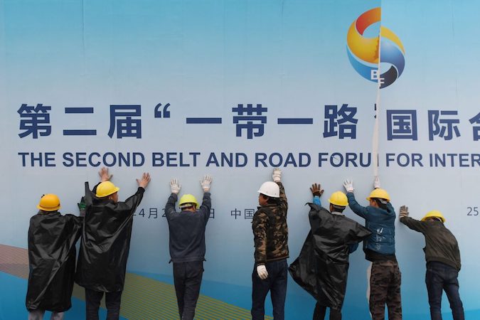Robotnicy zdejmują plakat forum nt. Inicjatywy pasa i szlaku z budynku, w którym odbyło się forum w Pekinie, 27.04.2019 r. (Greg Baker/AFP via Getty Images)