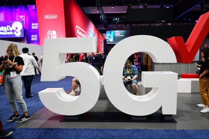 Użytkownicy telefonów komórkowych stoją obok wyświetlacza Verizon 5G na targach Electronic Entertainment Expo 2019, znanych również jako E3, Los Angeles, Kalifornia, 12.06.2019 r. (Frederic J. Brown/AFP/Getty Images)