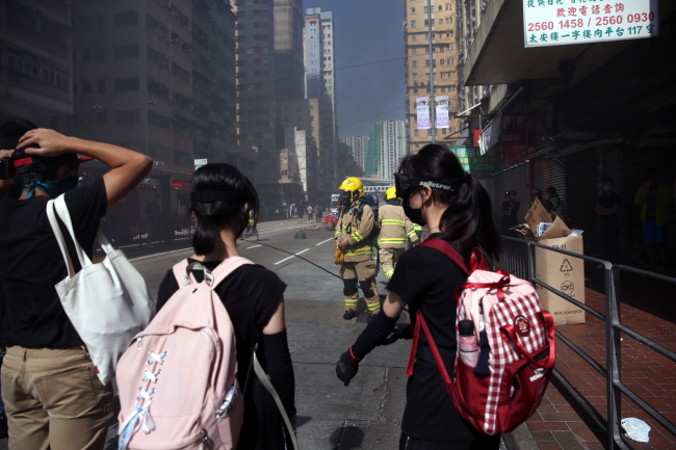 Protestujący stoją przed strażakami w miejscu, w którym protestujący został postrzelony przez funkcjonariusza policji, Sai Wan Ho, Hongkong, 11.11.2019 r. (JEROME FAVRE/PAP/EPA)