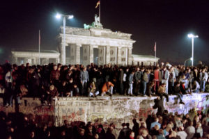 Tysiące młodych mieszkańców Berlina Wschodniego gromadzi się na szczycie muru berlińskiego, w pobliżu Bramy Brandenburskiej (w tle) 11.11.1989 r. (Gerard Malie/AFP/Getty Images)