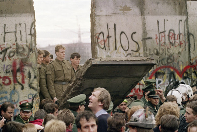 Mieszkańcy Berlina Zachodniego gromadzą się przed murem berlińskim 11.11.1989 r., obserwując wschodnioniemieckich strażników granicznych wyburzających fragment muru (Gerard Malie/AFP/Getty Images)