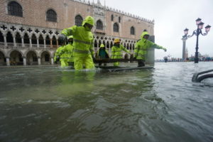 Pracownicy brną przez wody powodziowe w Wenecji, 12.11.2019 r. (ANDREA MEROLA/PAP/EPA)