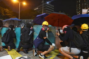 Protestujący na rzecz demokracji chronią się za barykadami podczas starć z policją w dzielnicy Jordan, Hongkong, 18.11.2019 r. (MIGEUL CANDELA/PAP/EPA)