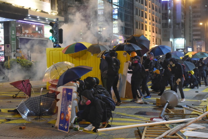 Protestanci na rzecz demokracji chronią się za barykadami, gdy policja strzela gazem łzawiącym podczas starć w dzielnicy Jordan, Hongkong, 18.11.2019 r. (MIGEUL CANDELA/PAP/EPA)