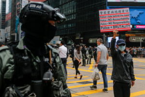 Protestujący na rzecz demokracji trzyma plakat, patrzy na niego policjant, protesty w Hongkongu, 19.11.2019 r. (FAZRY ISMAIL/PAP/EPA)