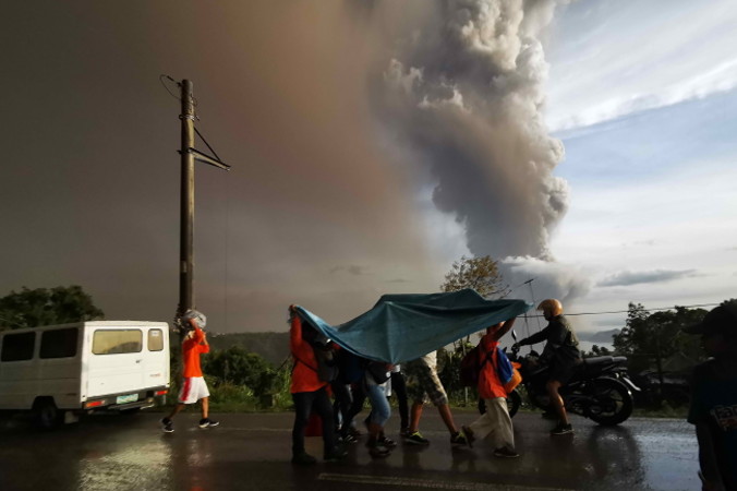 Ludzie chronią się pod dużą płachtą z tworzywa sztucznego przed chmurą popiołów wyrzuconą przez wulkan Taal nad miastem Tagaytay, Filipiny, 12.01.2020 r. (FRANCIS R. MALASIG/PAP/EPA)