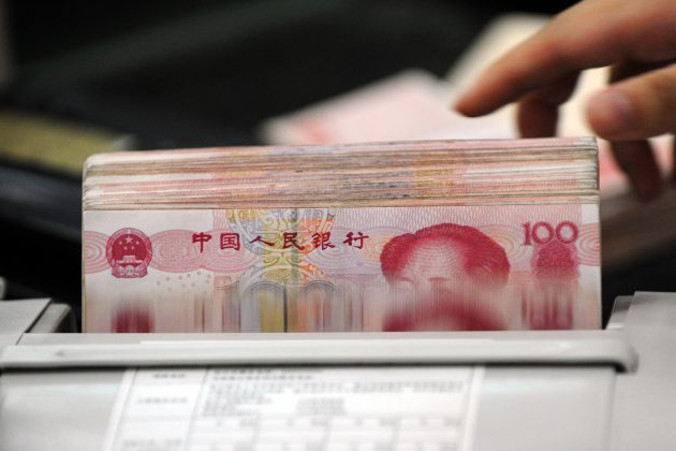 Urzędnik bankowy używa maszyny do liczenia plików banknotów 100-juanowych dla klienta banku w Hefei, prowincja Anhui, Chiny, 14.10.2010 r. (STR/AFP/Getty Images)