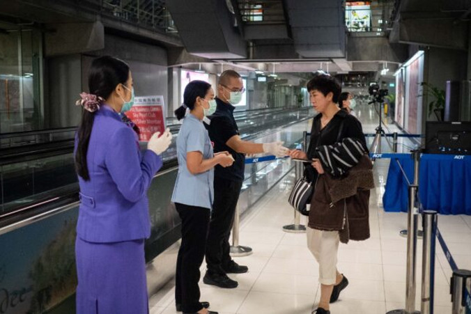 Urzędnicy ds. zdrowia publicznego rozdają informacje na temat monitorowania choroby po wykonaniu termicznych badań pasażerów przybywających z Wuhan w Chinach na lotnisko Suvarnabhumi w Bangkoku, Tajlandia, 8.01.2020 r. Tajlandia wprowadziła termiczne badanie pasażerów na 4 tajlandzkich lotniskach, w tym w Suvarnabhumi, Don Mueang, Phuket i Chiang Mai (Lauren DeCicca/Getty Images)