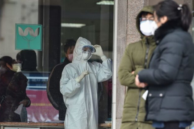 Pielęgniarka (pośrodku), ubrana w odzież ochronną, aby powstrzymać rozprzestrzenianie się niebezpiecznego wirusa, który został wykryty w Wuhan, patrzy na termometr w Piątym Szpitalu Wuhan, Wuhan, 24.01.2020 r. Według informacji z piątku zmarło już 26 osób zarażonych wirusem (Hector Retamal/AFP via Getty Images)