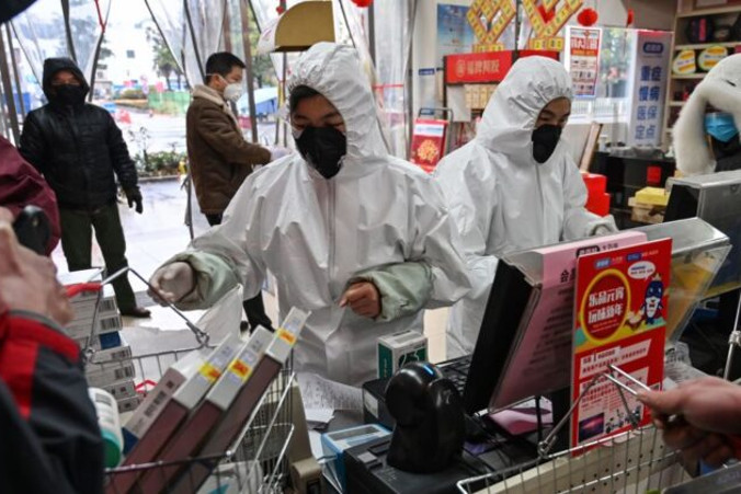 Pracownicy apteki w ubraniach ochronnych i maskach obsługują klientów w Wuhan, Chiny, 25.01.2020 r.<br /> (Hector Retamal/AFP via Getty Images)