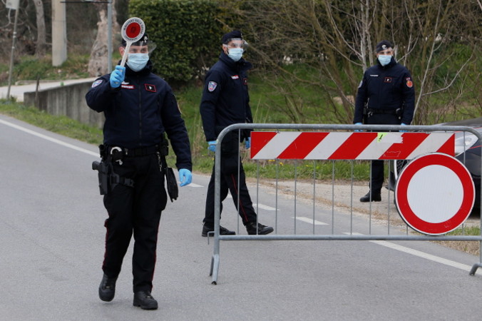 Oficerowie włoskiego Carabinieri w ochronnych maskach stoją przy blokadzie na drodze przy wjeździe do miasteczka Cinto Euganeo, niedaleko Padwy, północne Włochy, 24.02.2020 r. (NICOLA FOSSELLA/PAP/EPA)