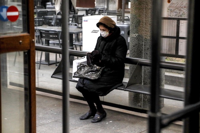 Kobieta w masce ochronnej siedzi na ławce w Mediolanie, północne Włochy, 27.02.2020 r.<br/>(MOURAD BALTI TOUATI/PAP/EPA)