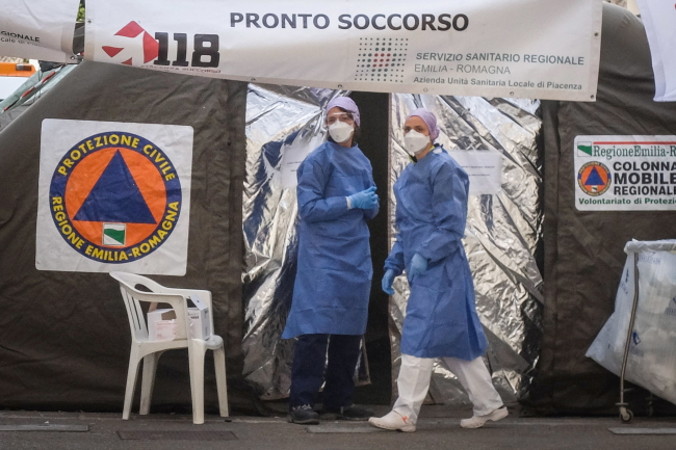 Dwie przedstawicielki służby zdrowia w kombinezonach ochronnych i maskach medycznych przed specjalistycznym oddziałem medycznym, zbudowanym przed izbą przyjęć szpitala w Piacenza, Włochy, 27.02.2020 r.<br/>(MATTEO CORNER/PAP/EPA)